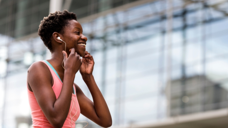 Woman smiles and adjusts her earphones before a relaxed mindfulness run
