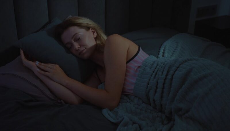 A close-up view of the woman's face and hands as she sleeps peacefully in her bed