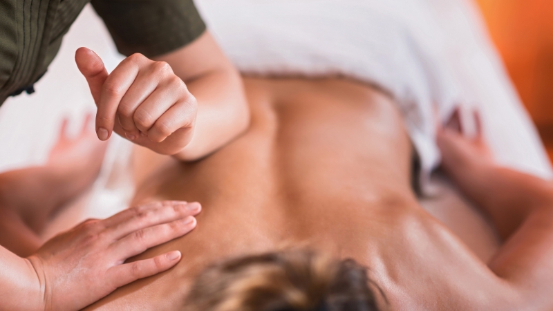 A therapist performs a deep massage on a person’s back to help reduce muscle inflammation