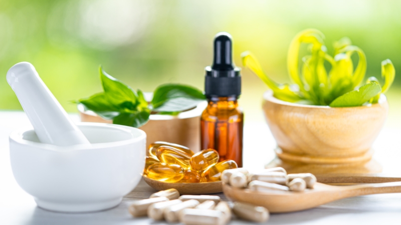 Herbs, capsules, and oils arranged on a table show natural remedies for muscle inflammation relief