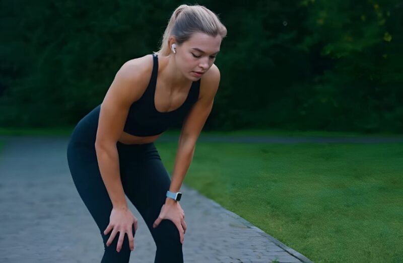 A runner pauses, catching her breath in a park