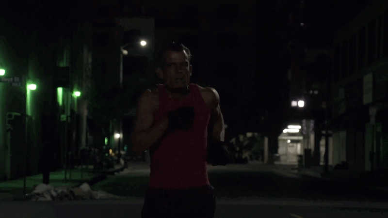 A man in a red tank top runs alone through dark city streets in Skid Row Marathon