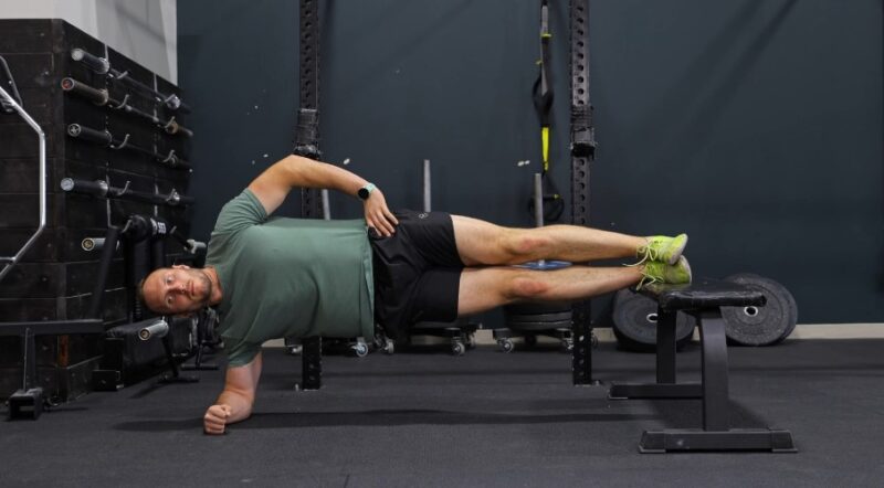Man performing a side plank with leg raise, engaging core muscles