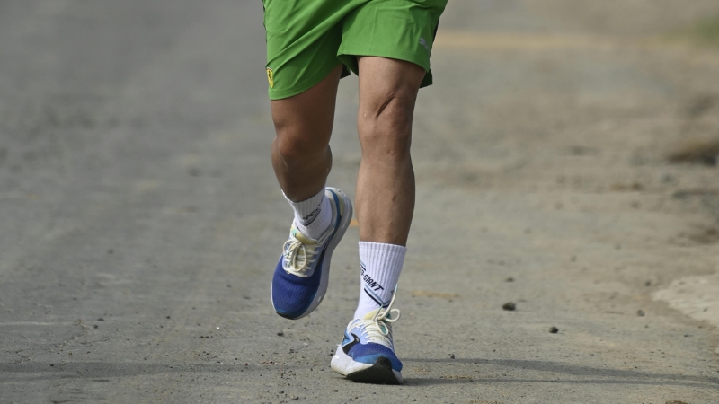Runner in green shorts training on a quiet road during week 1 of a half marathon training plan