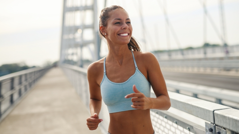 Woman running on a bridge, smiling during week 4 of her half marathon training routine