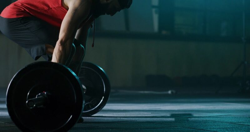 Athlete preparing to lift a barbell, highlighting the importance of balancing training volume in post-weightlifting progress