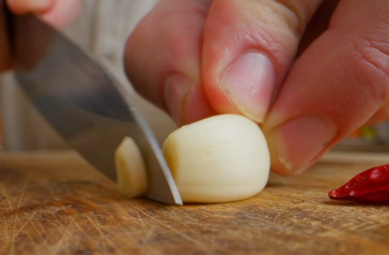 Close-up of a knife cutting into a garlic clove