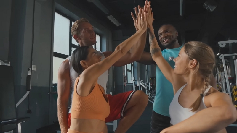 A group of people in a gym smile and high-five each other after completing a workout