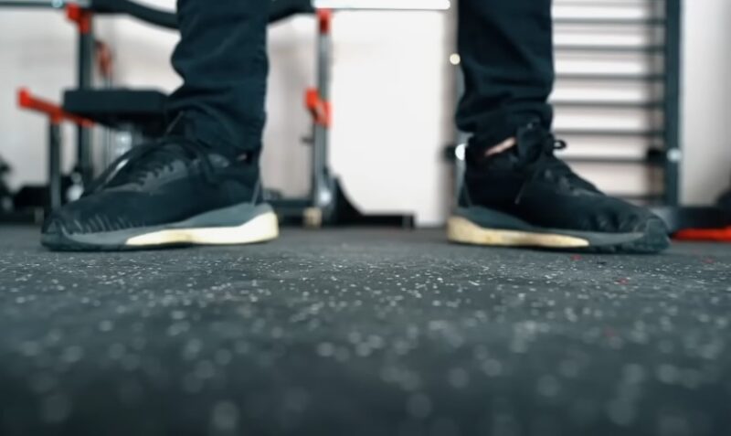 A person stands on a gym floor, wearing sneakers
