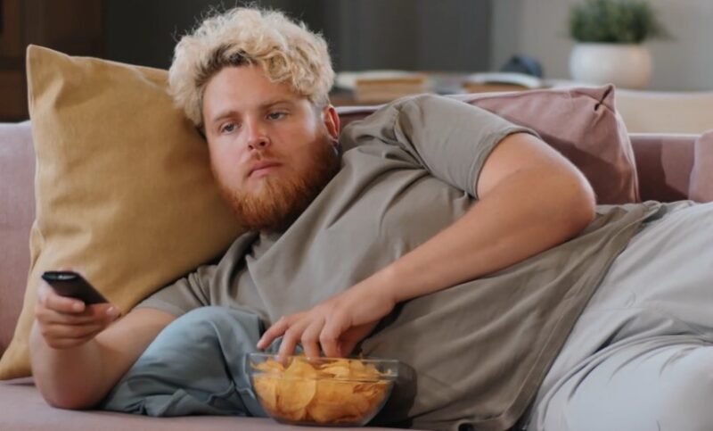 Man eating chips while watching TV from a couch