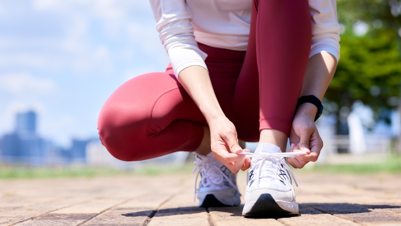 Person tying shoelaces outdoors before starting a morning run