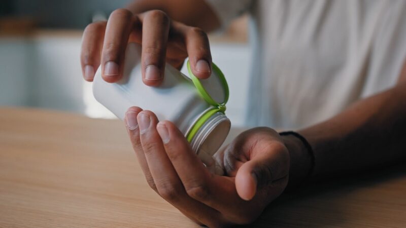 Close-up of hands holding a supplement bottle, often used to support post-weightlifting recovery