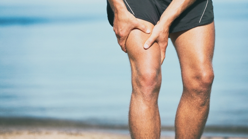 Man holding his thigh in pain during a run, indicating discomfort that may require rest
