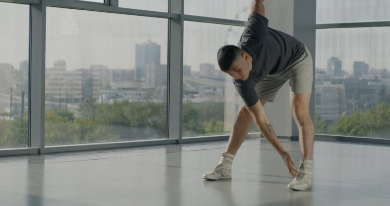 Man stretching indoors to improve flexibility and aid post-weightlifting recovery