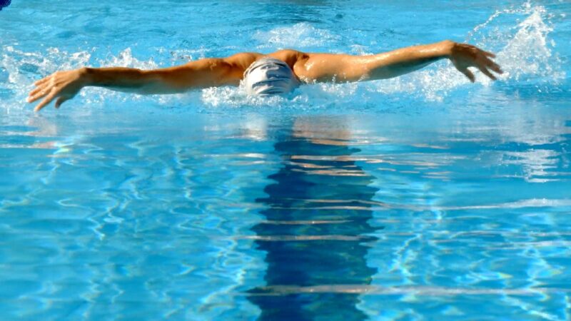 Swimmer doing butterfly stroke while swimming laps in a pool