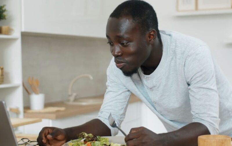 Man eating while looking at a laptop