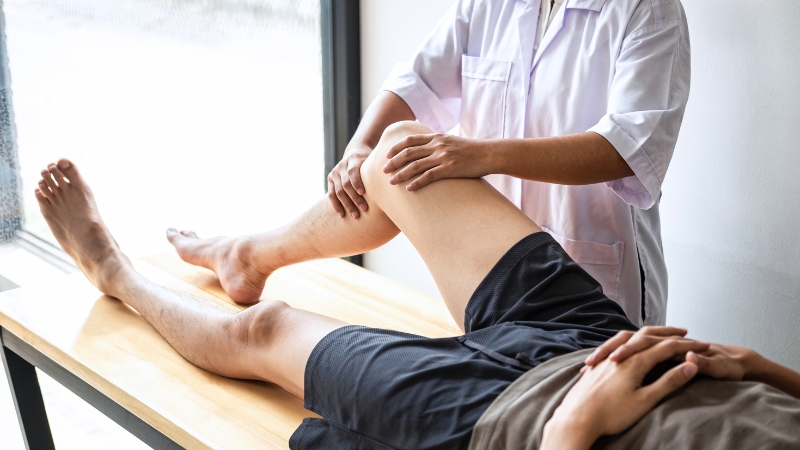 Physiotherapist examining a patient’s leg to assess pain and mobility issues