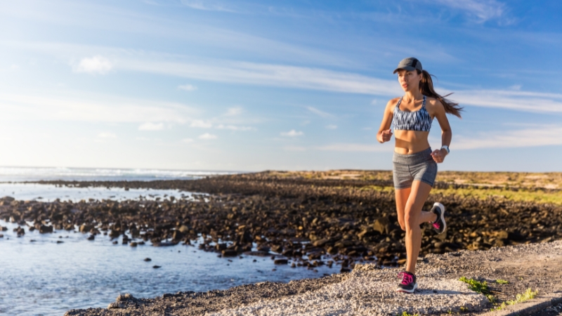 Woman running outdoors by the ocean on a sunny day