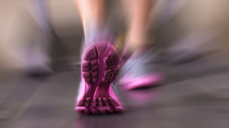 Close-up of a person running on a treadmill with focus on the sole of a pink athletic shoe in motion