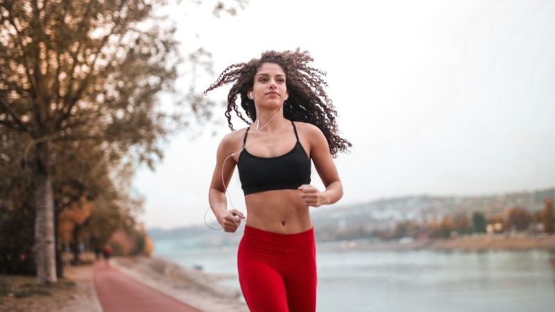 Woman jogging outdoors by a riverside path, showing how weekly runs can support calorie goal
