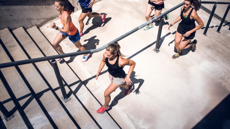 Group of runners climbing outdoor stairs, highlighting how effort and terrain increase calorie burn
