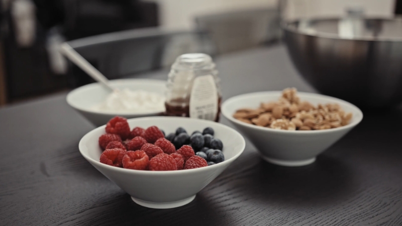 Bowls of fresh berries, granola, yogurt, and honey arranged on a table as a healthy pre-workout meal option