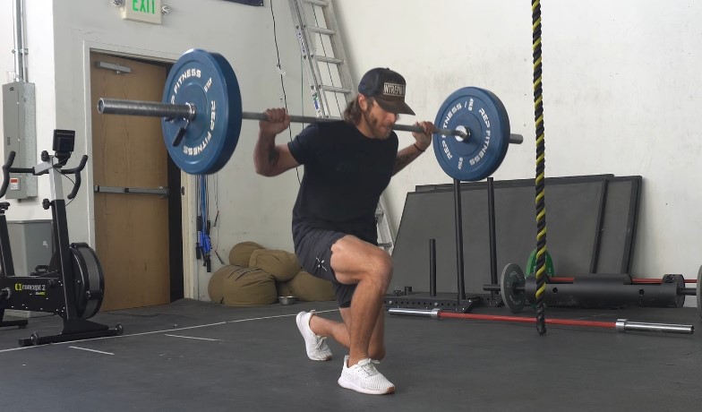 Man lifting weights wearing running shoes