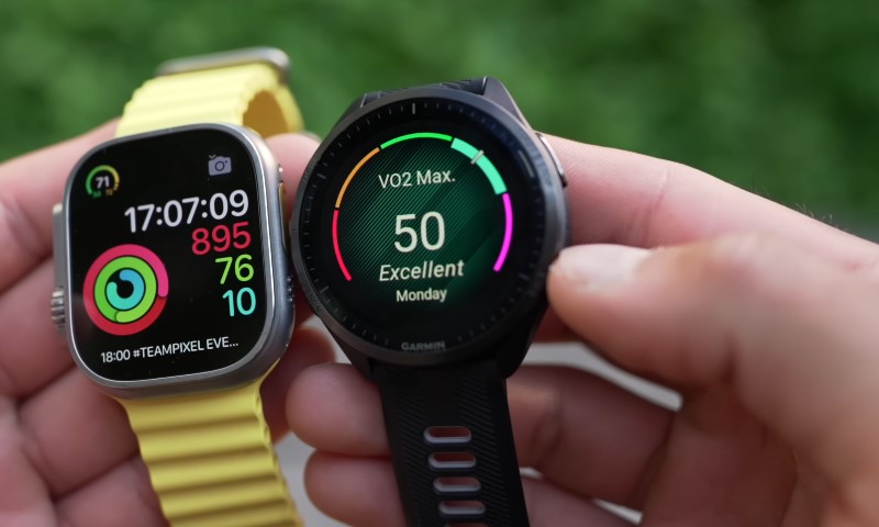 Two smartwatches, an Apple Watch Ultra with yellow band and a Garmin displaying a VO2 Max score of 50, held side-by-side