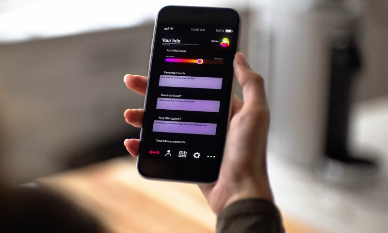 Woman holding a phone, looking at fitness app results