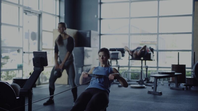 Indoor gym training session with a rowing machine and strength exercises in the background