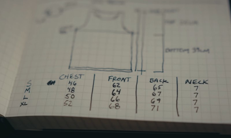 Sketch of a sleeveless top with handwritten size chart on grid paper