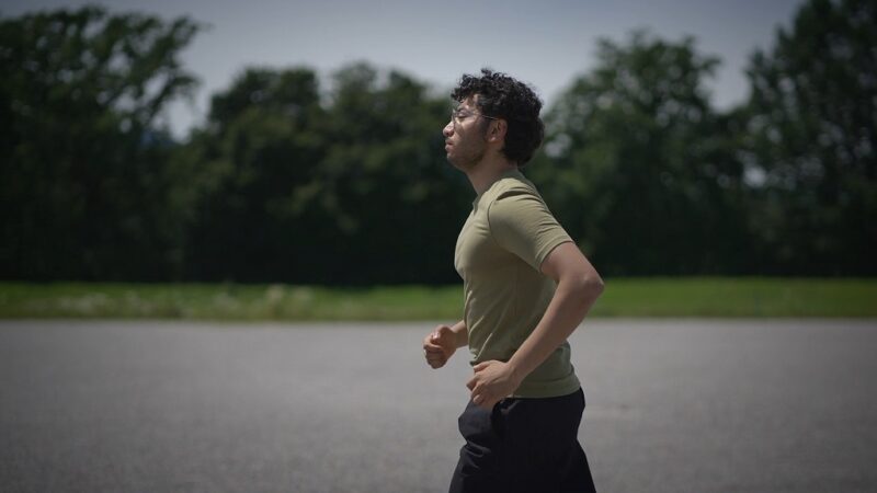 Person jogging outdoors on a paved path with trees in the background
